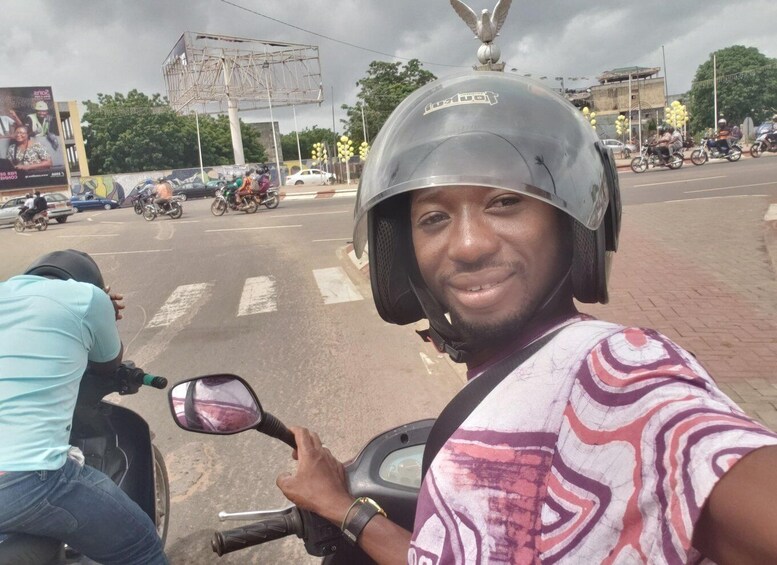A person on a motorcycle with a helmet, holding a selfie stick. 4