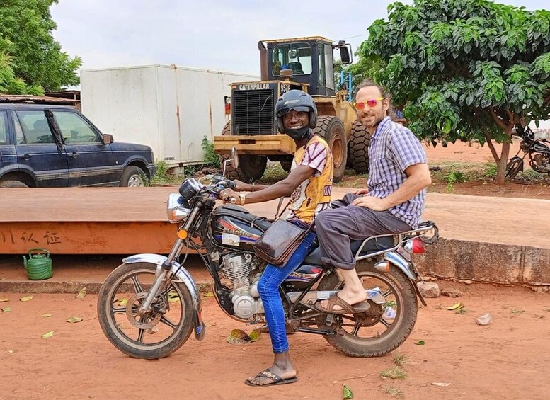 A man on a motorcycle with a large vehicle and trees in the background. 3