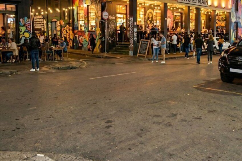 A street with a restaurant named 'Main' and people dining outside. 1