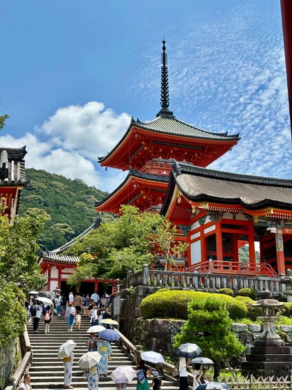 A traditional Japanese temple with red and white architecture, surrounded by lush greenery and a clear blue sky. 2
