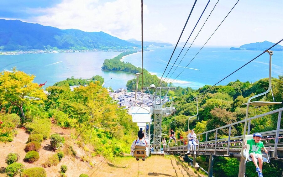 A cable car with passengers overlooking a coastal landscape with mountains in the distance. 5