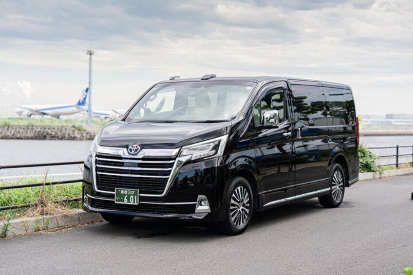 A black Toyota van parked on a road with a river and a bridge in the background. 5