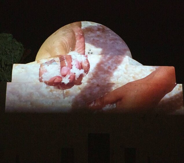 A hand holding a piece of food, possibly a pastry, with a dark background. 4