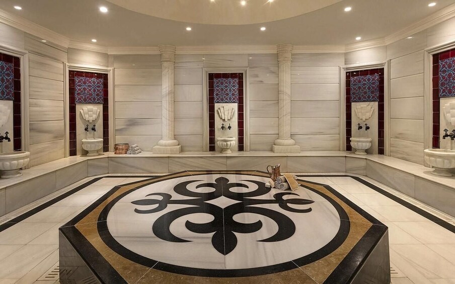 A luxurious bathroom with a large central floor design, marble walls, and decorative columns. 5