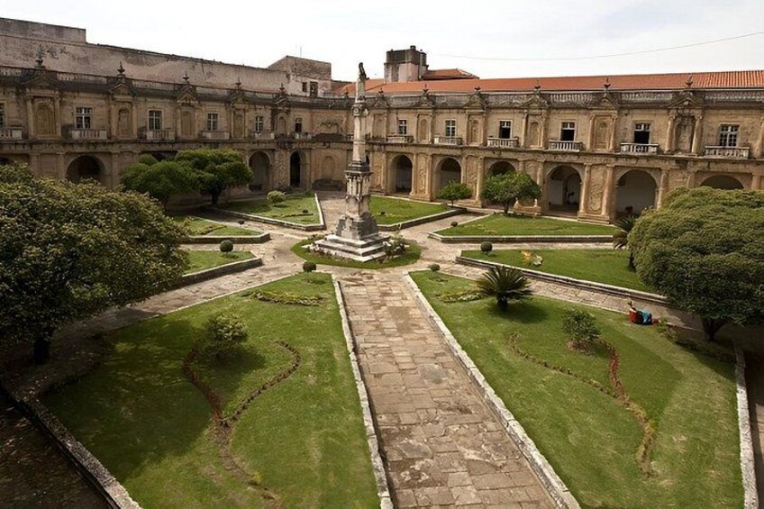 A courtyard with a central fountain, surrounded by manicured lawns and a historic building facade. 5