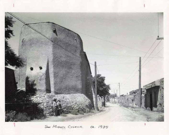 A large stone church with a prominent bell tower, surrounded by a rural street and simple houses. 4