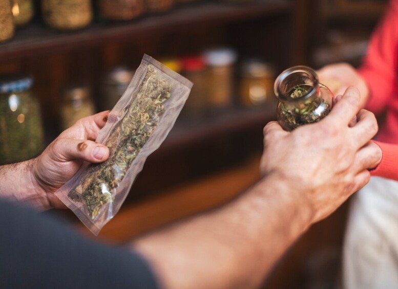 A person holding a bag of dried herbs and a small jar of the same substance. 4