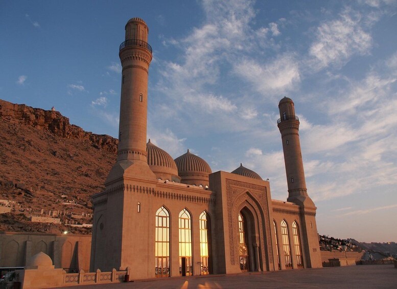 A mosque with two minarets and a large central dome, set against a hilly backdrop. 4