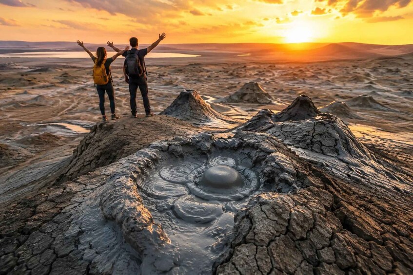 Two people standing on a rocky terrain with a large crater in the foreground. 1