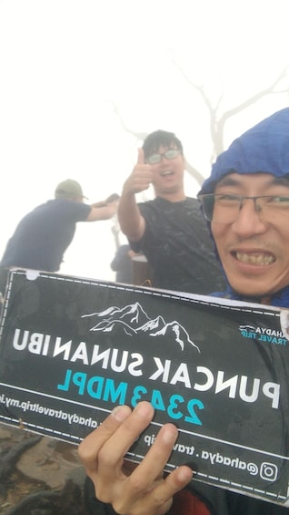 A person holding a sign with 'PUNAK SANDALP' and a mountain graphic. 2