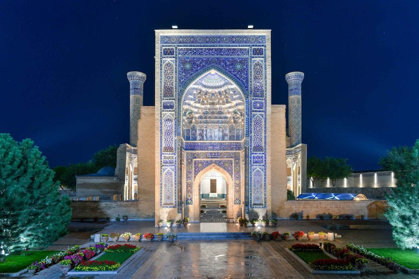 A night view of a historic building with intricate blue tile work and two tall minarets. 4