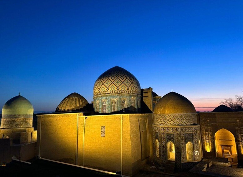 A mosque with multiple domes and intricate tile work, illuminated at dusk. 2