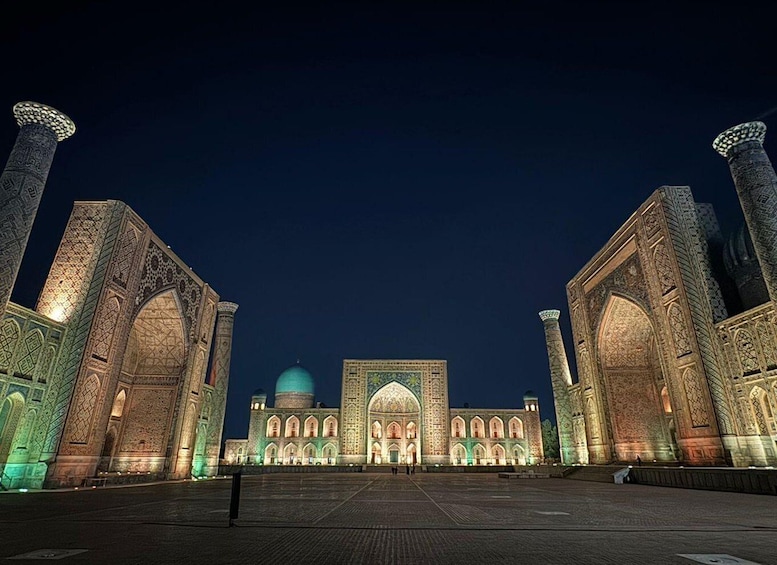 A grand mosque with intricate tile work and a large dome, illuminated at night. 5