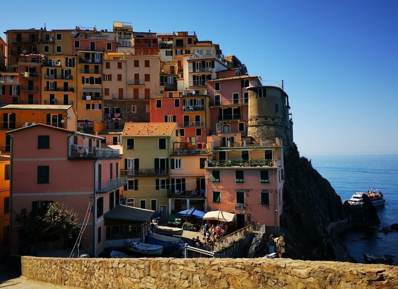 A coastal town with colorful buildings, a stone wall, and boats at the harbor. 5