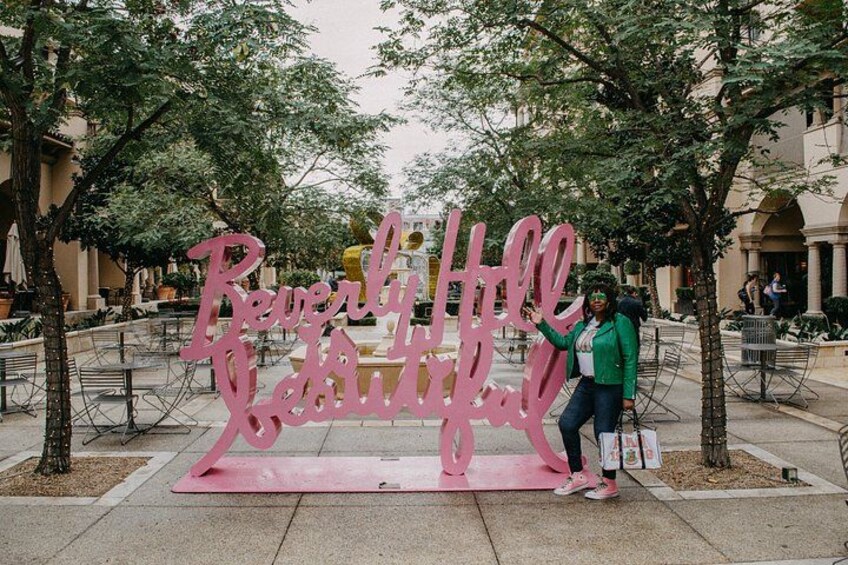 A pink sign with the text 'Reverly Hill' in a public outdoor area with trees and benches. 3