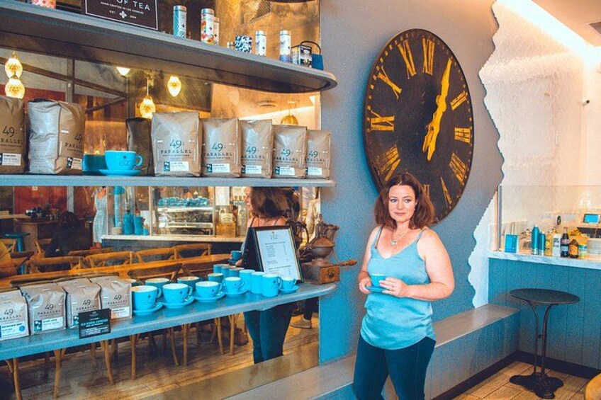 A coffee shop interior with a large clock, coffee bags, and blue cups on display. 2