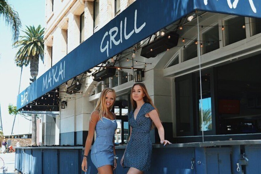 A bar named 'Makai Grill' with a blue awning and palm trees in the background. 2