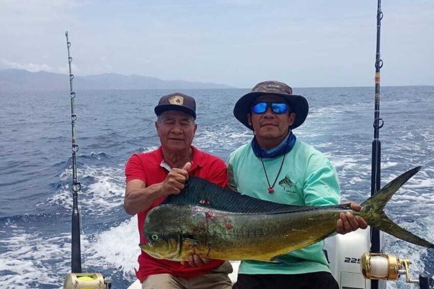 Two people on a boat holding a large fish. 1