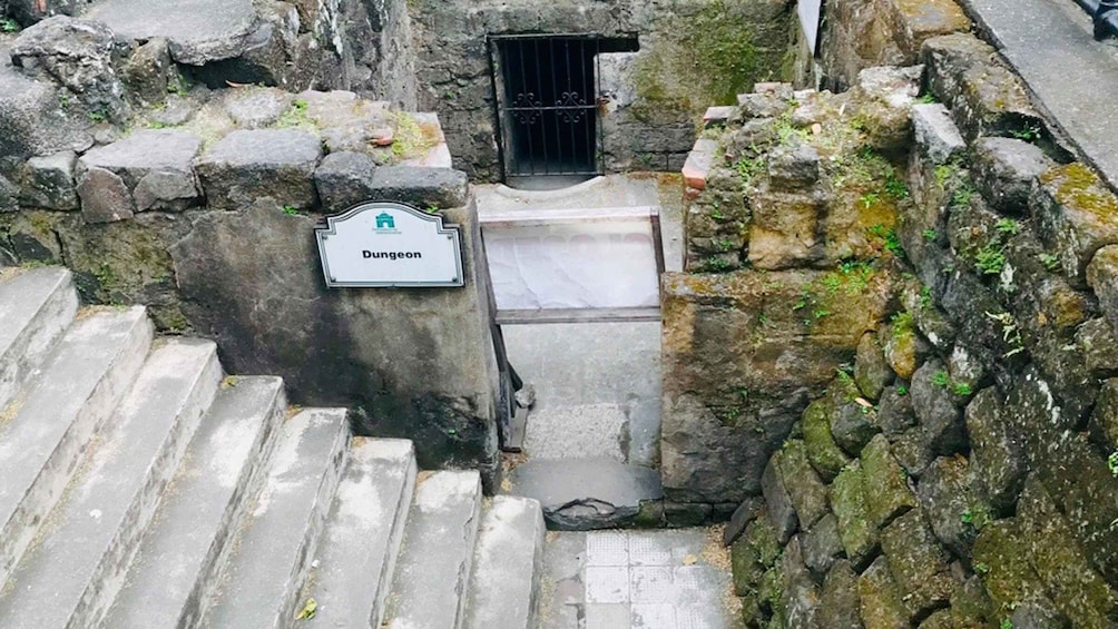A stone staircase leading to a dungeon entrance with a sign. 3
