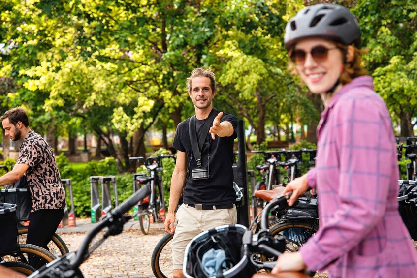 People interacting with bicycles in an outdoor setting with trees and a brick pathway. 5