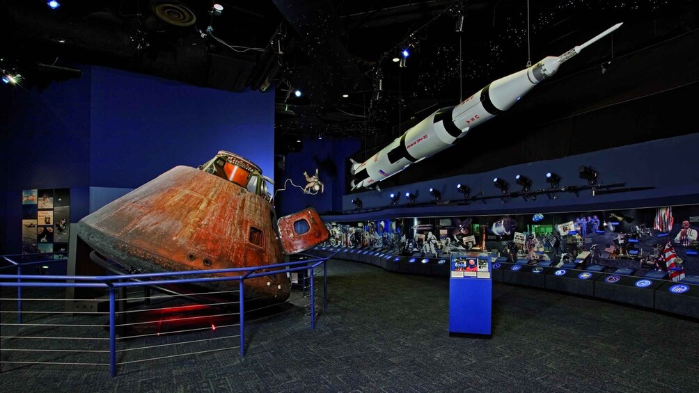 A museum exhibit with a large rocket model, a space shuttle, and various space exploration artifacts. 1
