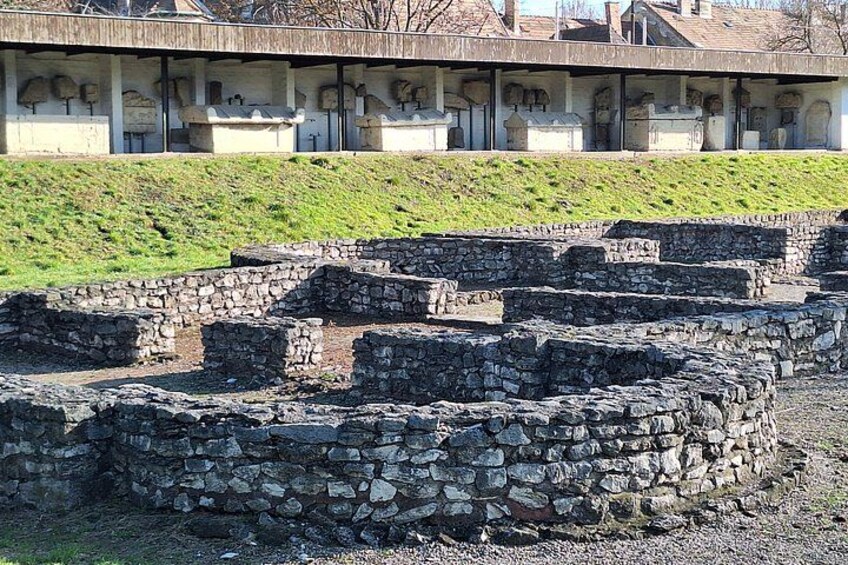 Ancient stone ruins with a modern building in the background. 2