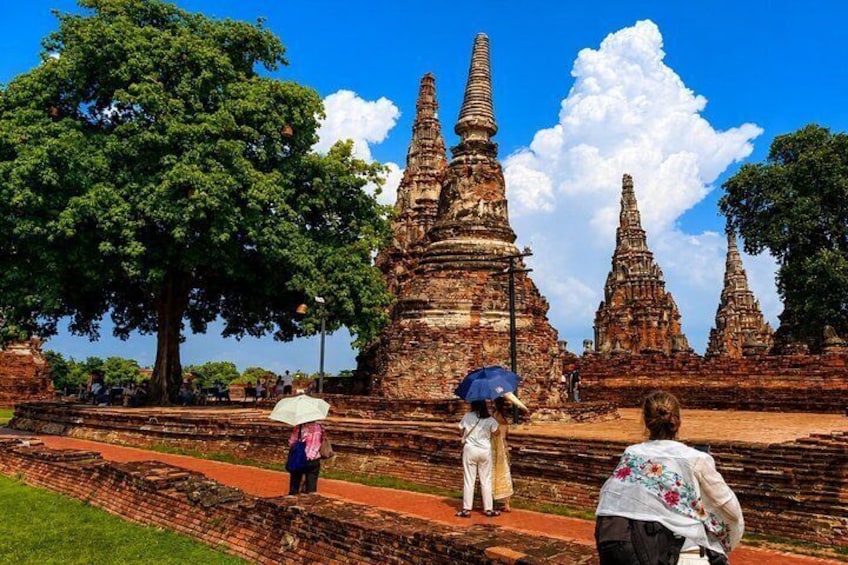 Ancient temple ruins with multiple tiered structures, a large tree, and visitors. 3