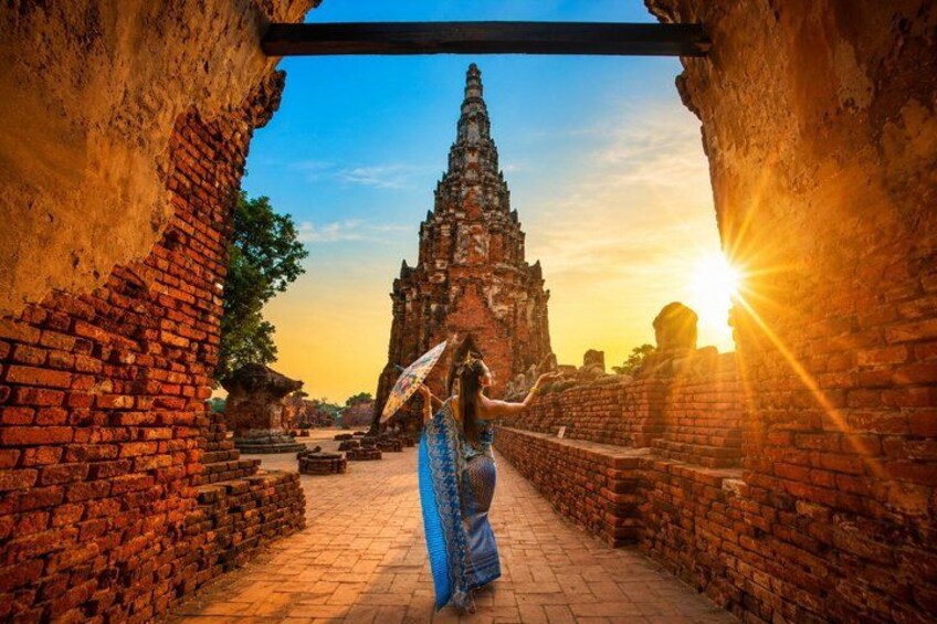 A person in traditional attire walking through an ancient brick structure with a temple in the background. 3