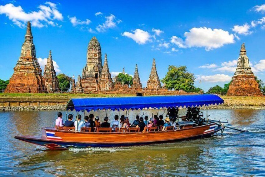 A boat with passengers, a blue canopy, and ancient temple ruins in the background. 1