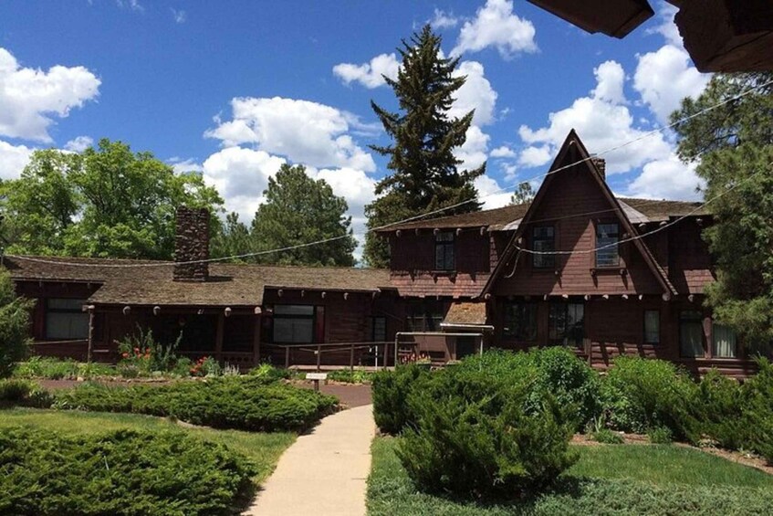 A wooden building with a sloped roof, surrounded by a well-maintained garden and a clear sky. 1
