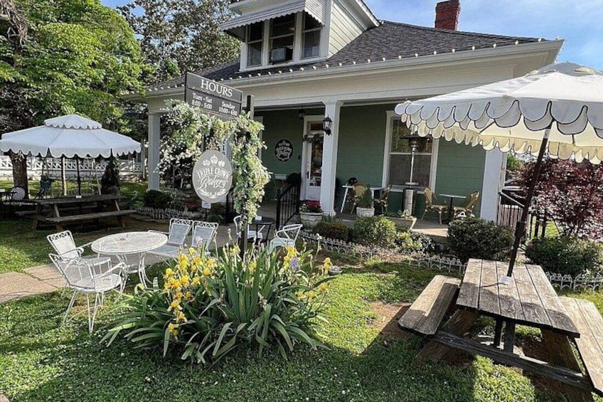 A house with a sign reading 'HOURS' and outdoor seating with umbrellas. 2