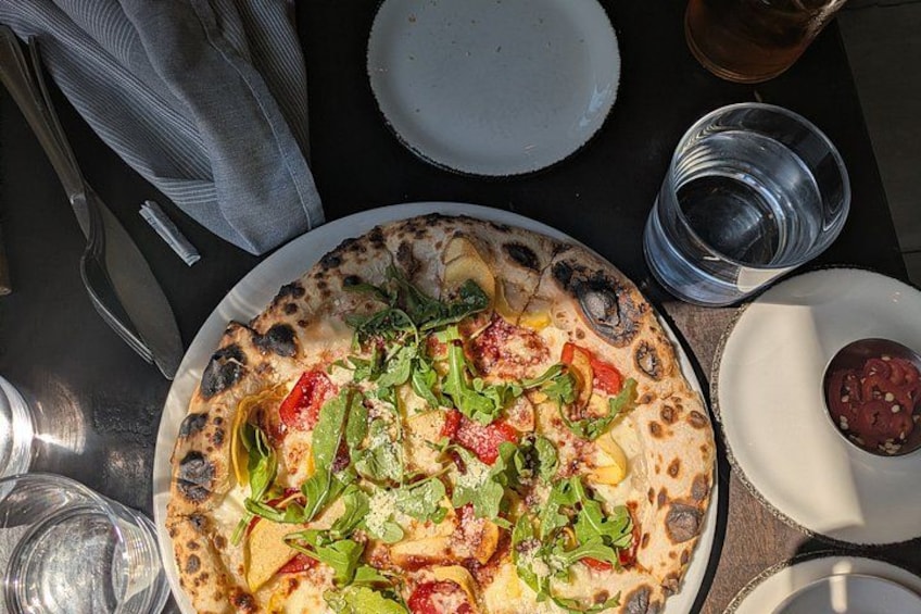 A pizza with various toppings on a plate, accompanied by a glass of water and a cup. 5