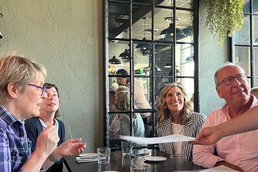 A group of people sitting at a table in a restaurant with a large window in the background. 3