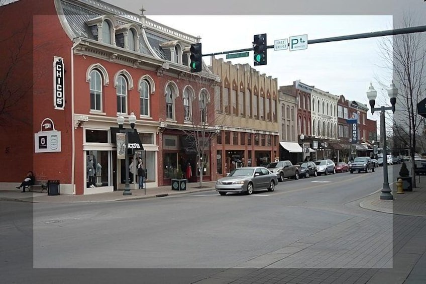 A street with vintage buildings, a traffic light, and parked cars. 4