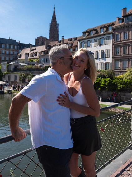 Ein Paar umarmt sich auf einer Brücke, im Hintergrund historische Gebäude und ein Turm. 5
