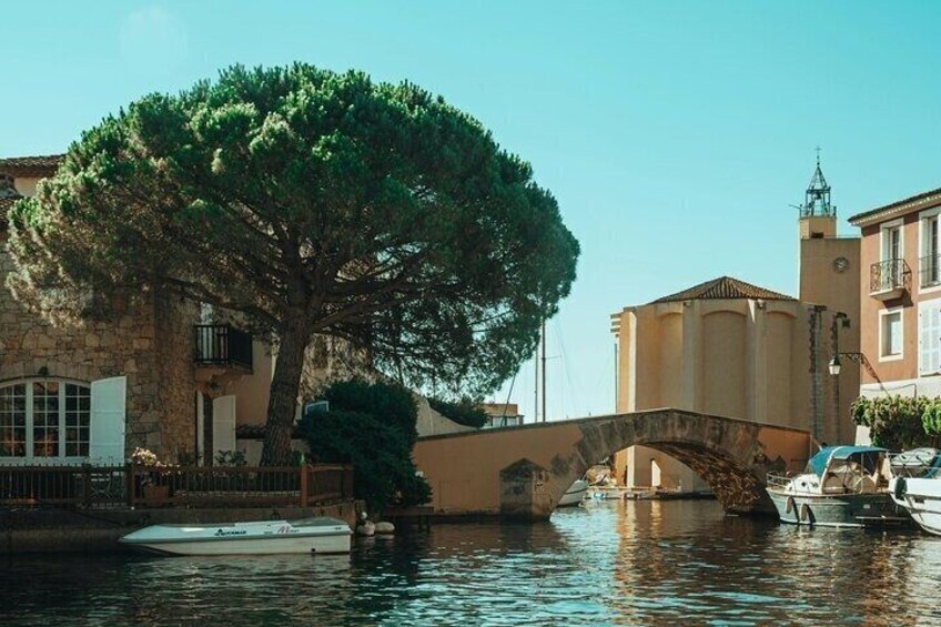 A stone bridge over water, a tree, and buildings with a tower. 4