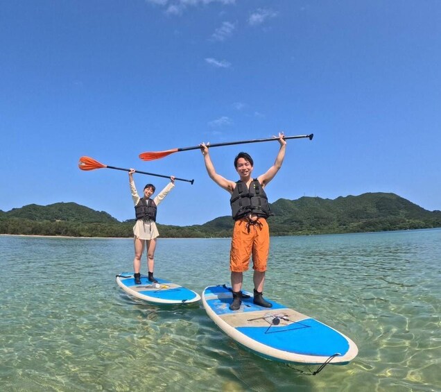 Two people paddleboarding on clear water with a hilly landscape in the background. 4