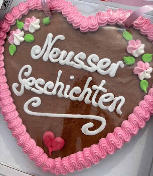 A heart-shaped cake with the words 'Neusser Geschichten' written on it. 2