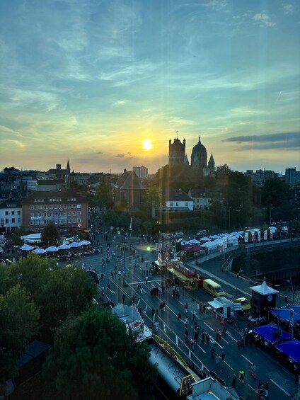 A cityscape with a prominent cathedral and a busy street market during sunset. 5