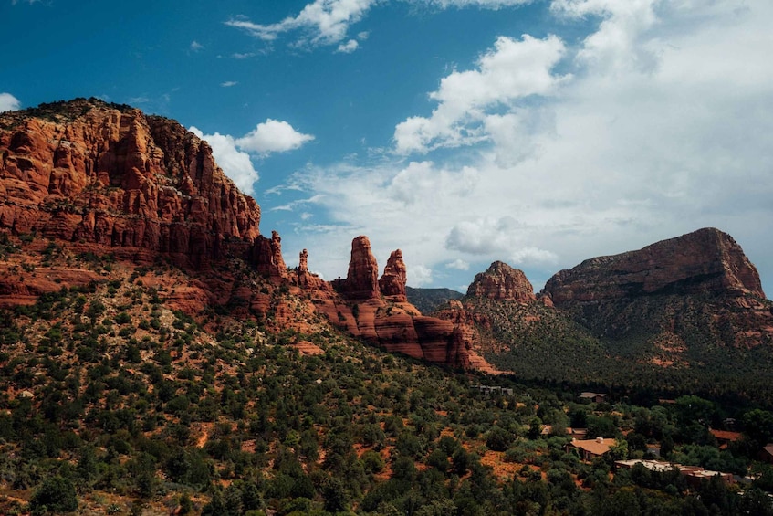 A mountainous landscape with red rock formations and scattered greenery. 5