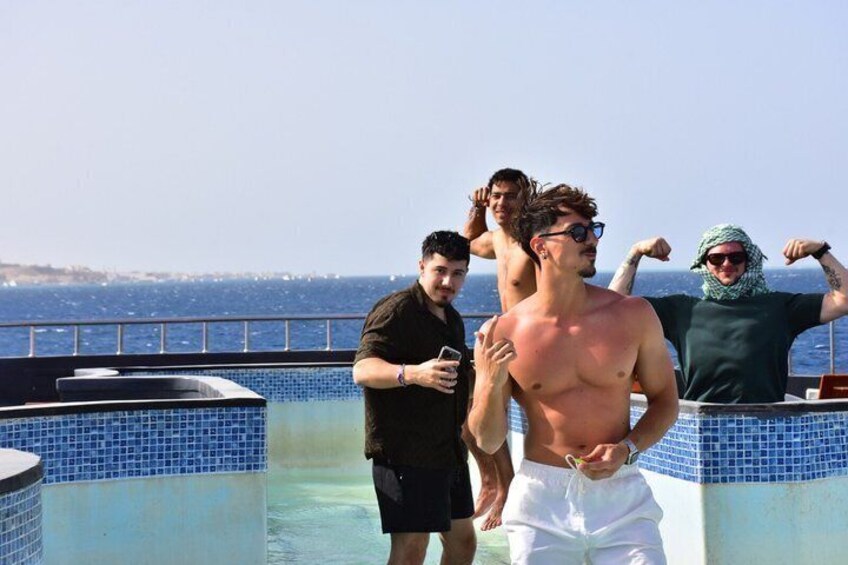 A group of people by a pool with a view of the sea. 4