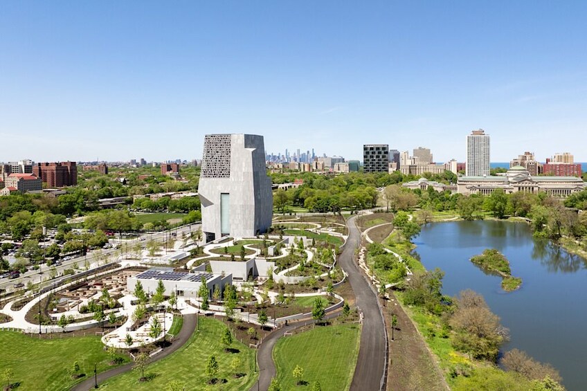 Un paisaje urbano con un edificio moderno destacado, un lago y vegetación circundante. 3