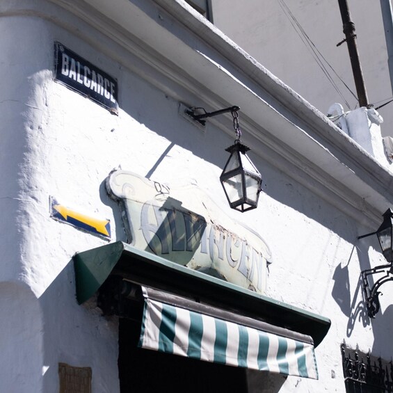 A building with a sign that reads 'BALCARCE' and a green and white striped awning. 4