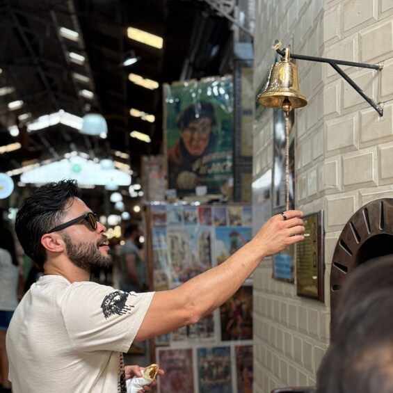 A person ringing a bell mounted on a brick wall. 1