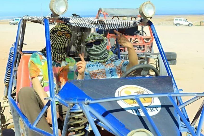 A blue vehicle with a large tire and a person pointing outwards. 1