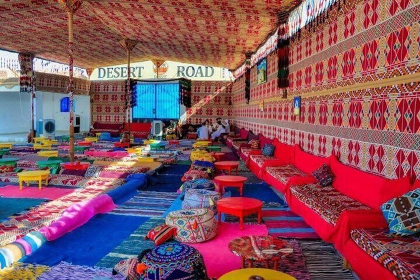 A colorful interior with patterned walls, a blue carpet, and red and yellow seating areas. 2