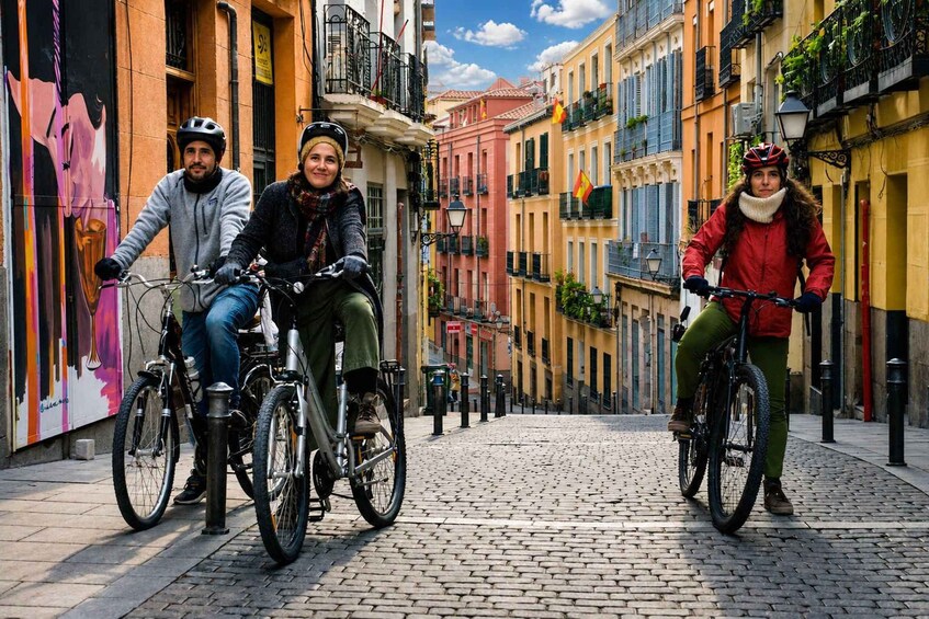 Tre cyklister på en kullerstensgata i en europeisk stad. 3