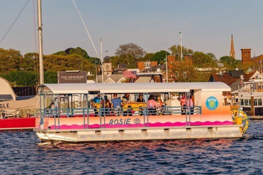 A boat named 'ROSIE' docked at a harbor with buildings and a church in the background. 5