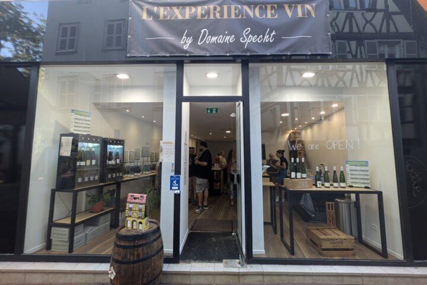 A storefront with a sign reading 'L'EXPERIENCE VIN by Danielle Specht' and a 'We are OPEN!' sign. 4