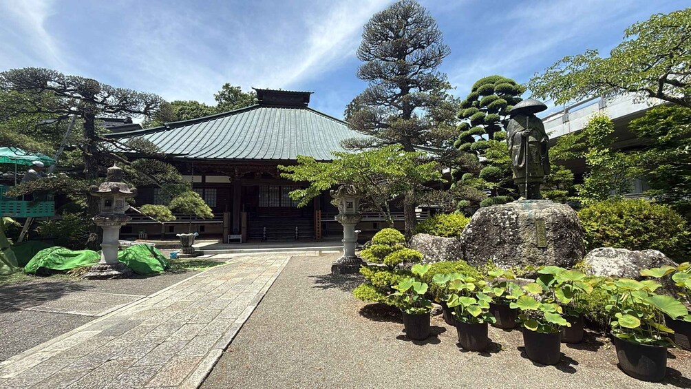 A traditional Japanese building with a tiled roof, surrounded by well-maintained greenery and stone lanterns. 1